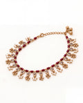 Bloom Drop red anklet laid in an oval with clear teardrop stones, red beads and pearl and bell tassels