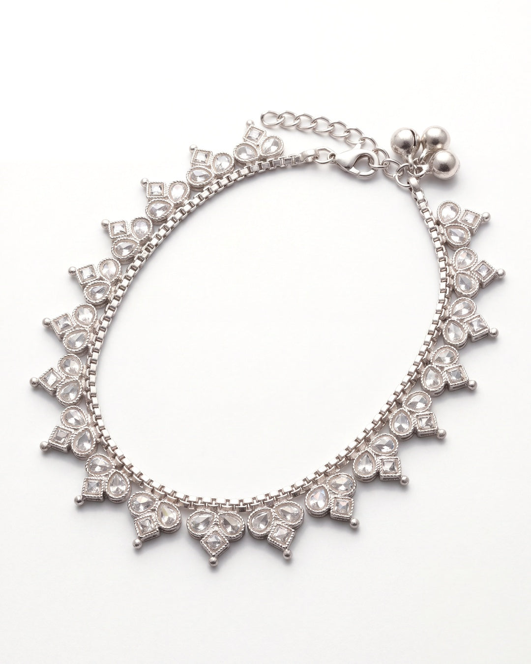 Vera silver-tone anklet laid in an oval with a close fringe of clear trefoil stone motifs and three small bells