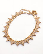 Vera gold-tone anklet laid in an oval with a close fringe of champagne trefoil stone motifs and three textured bells