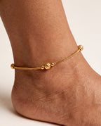 Luma Glow gold-tone anklet worn on an ankle with a textured bead station