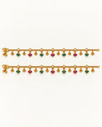 Pair of Coral Bloom gold-tone anklets laid flat with clear pear-shaped accents and alternating green and magenta bead drops