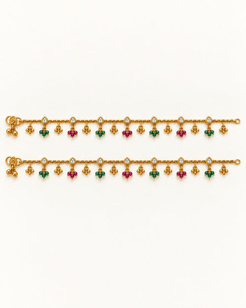 Pair of Coral Bloom gold-tone anklets laid flat with clear pear-shaped accents and alternating green and magenta bead drops
