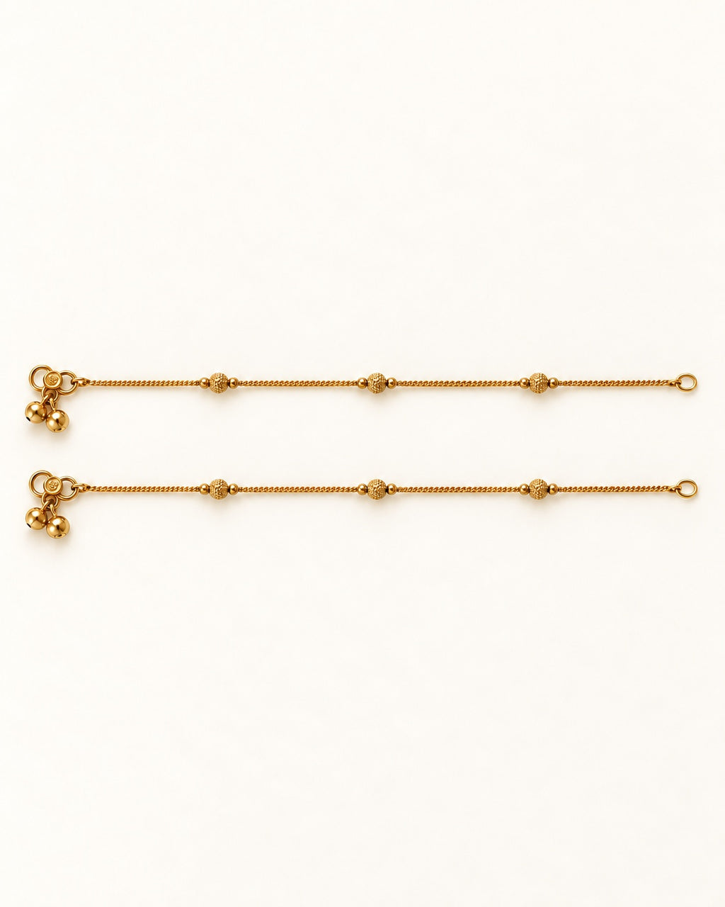 Pair of Luma Glow gold-tone anklets laid flat with three textured bead stations on each anklet