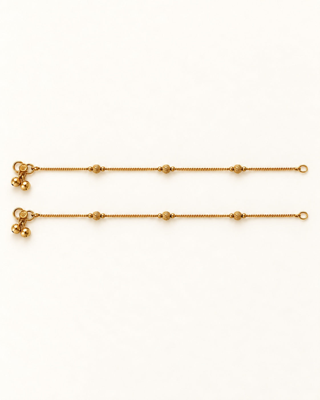 Pair of Luma Glow gold-tone anklets laid flat with three textured bead stations on each anklet