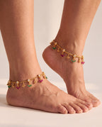 Pair of Coral Bloom gold-tone anklets worn on both ankles with clear pear-shaped accents and colored bead drops