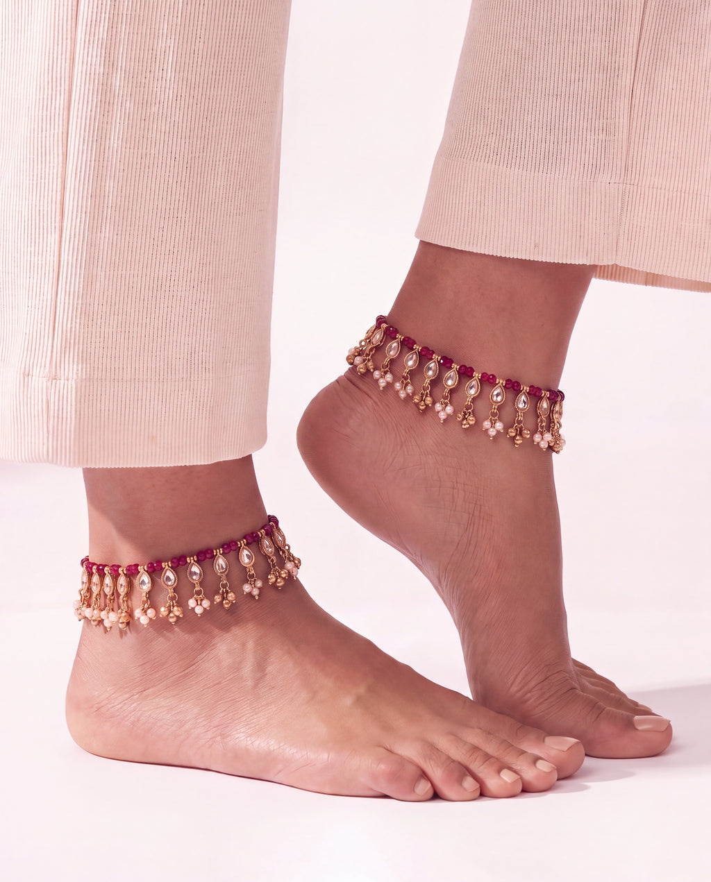 Bloom Drop red anklets worn on both ankles with cream trousers