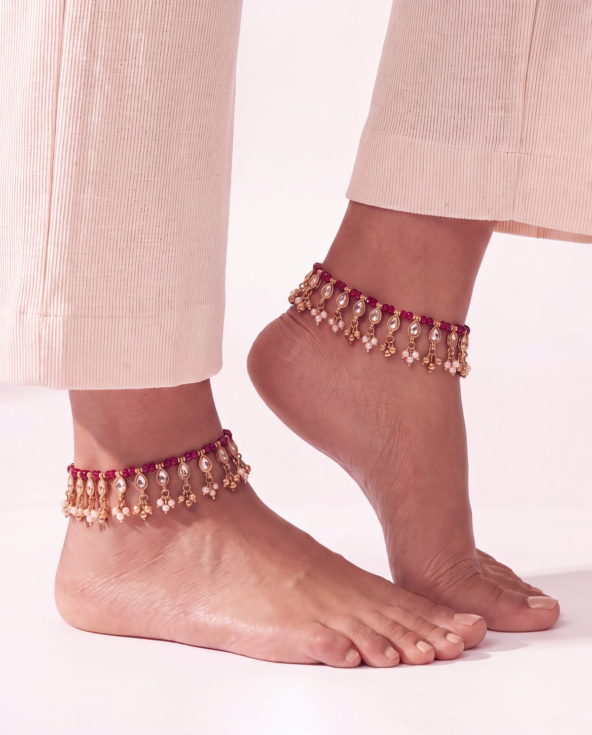 Bloom Drop red anklets worn on both ankles with cream trousers