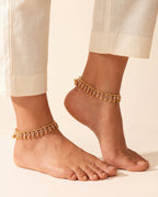 Margot Chime gold-tone anklets worn on both ankles with cream trousers