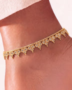 Close-up of the Vera gold-tone anklet on the ankle, showing champagne pear and square stones in rope-edged settings