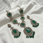 Detail flatlay of the gold-tone emerald statement necklace and matching earrings with green detailing
