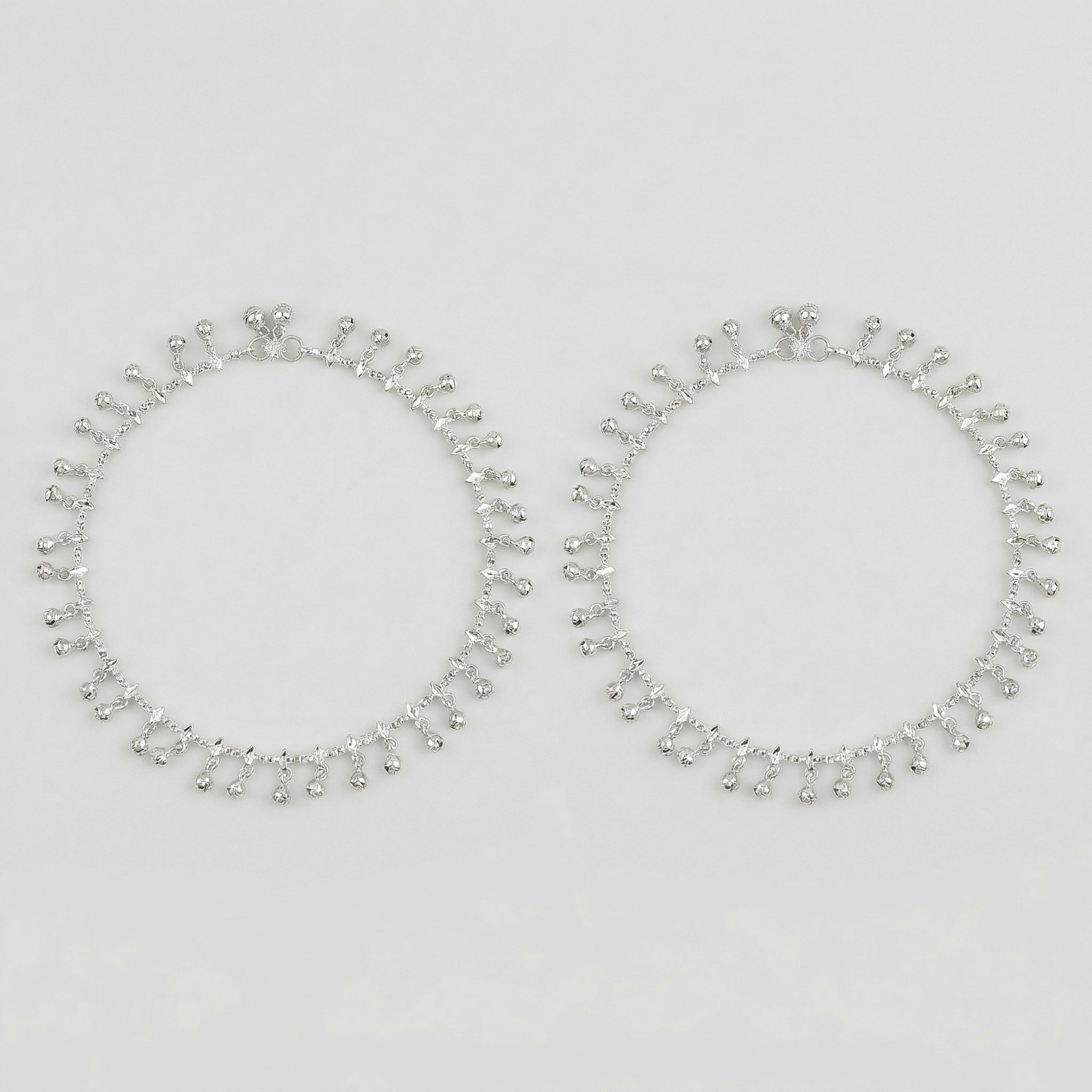 Shimmering Charm Anklets pair of silver-tone ghungroo bell payals on gray background