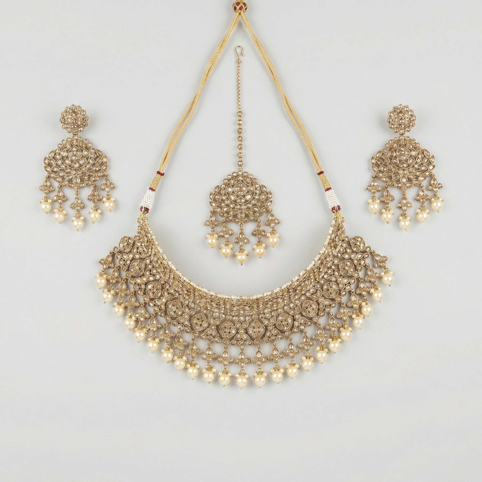 Regal Pearl Necklace Set gold polki bib with pearl drops, chandelier earrings, and maang tikka on gray background
