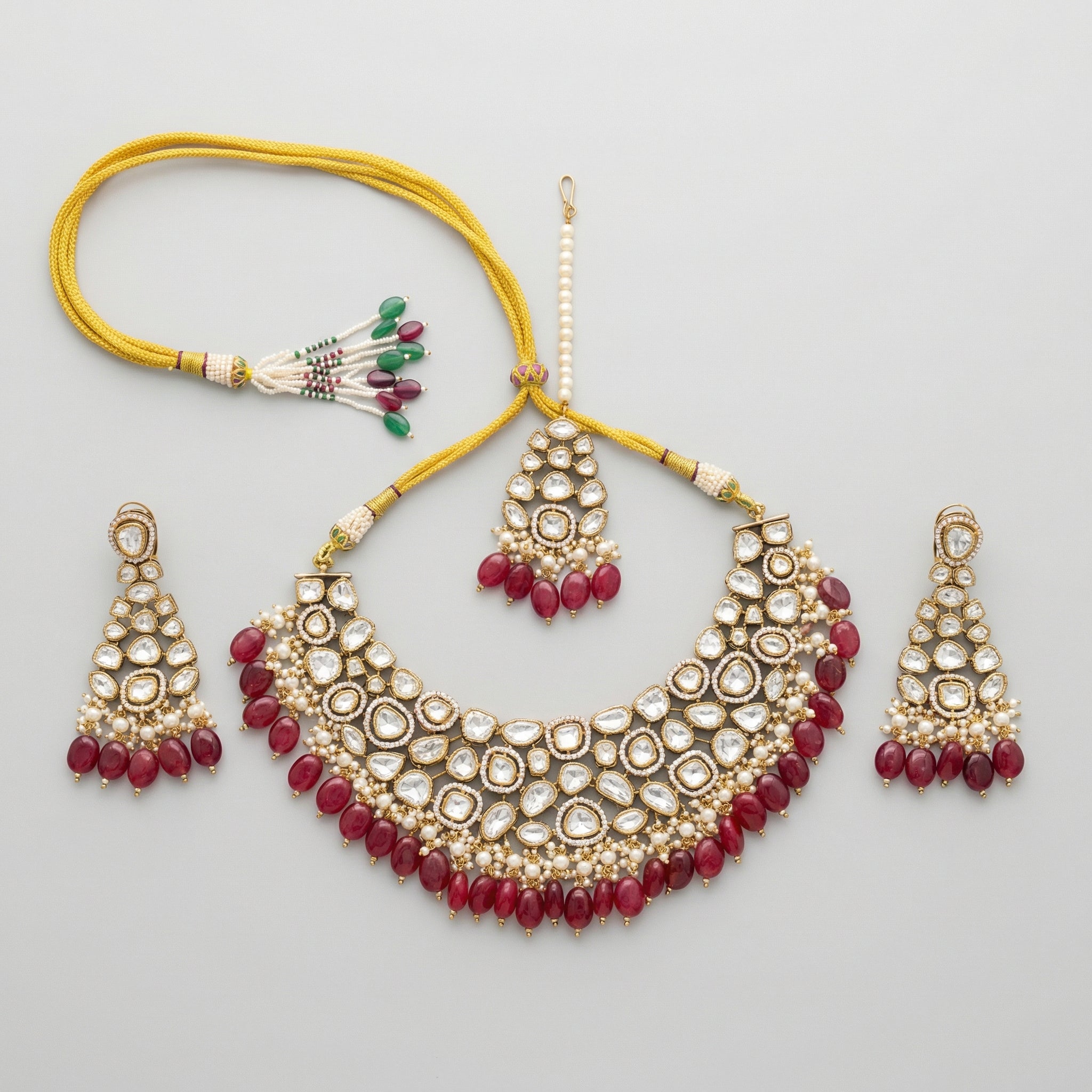 Detail flatlay of the red kundan necklace set, highlighting the stonework and earrings.