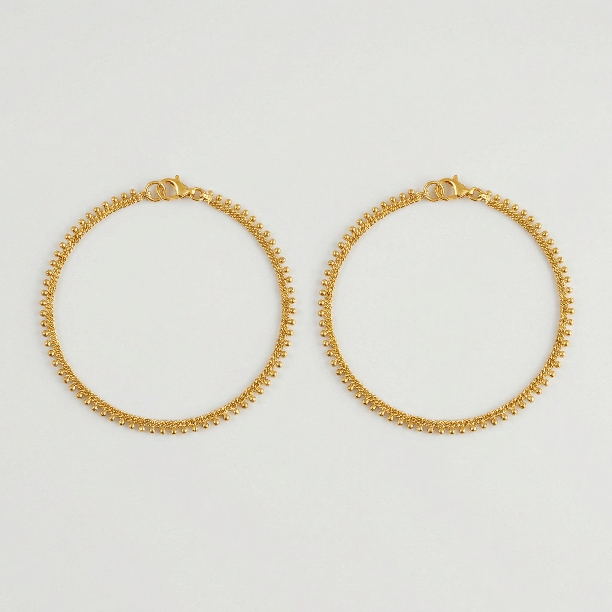 Golden Dotted Chain Anklets pair of gold twisted-chain payals with bead fringe on gray background