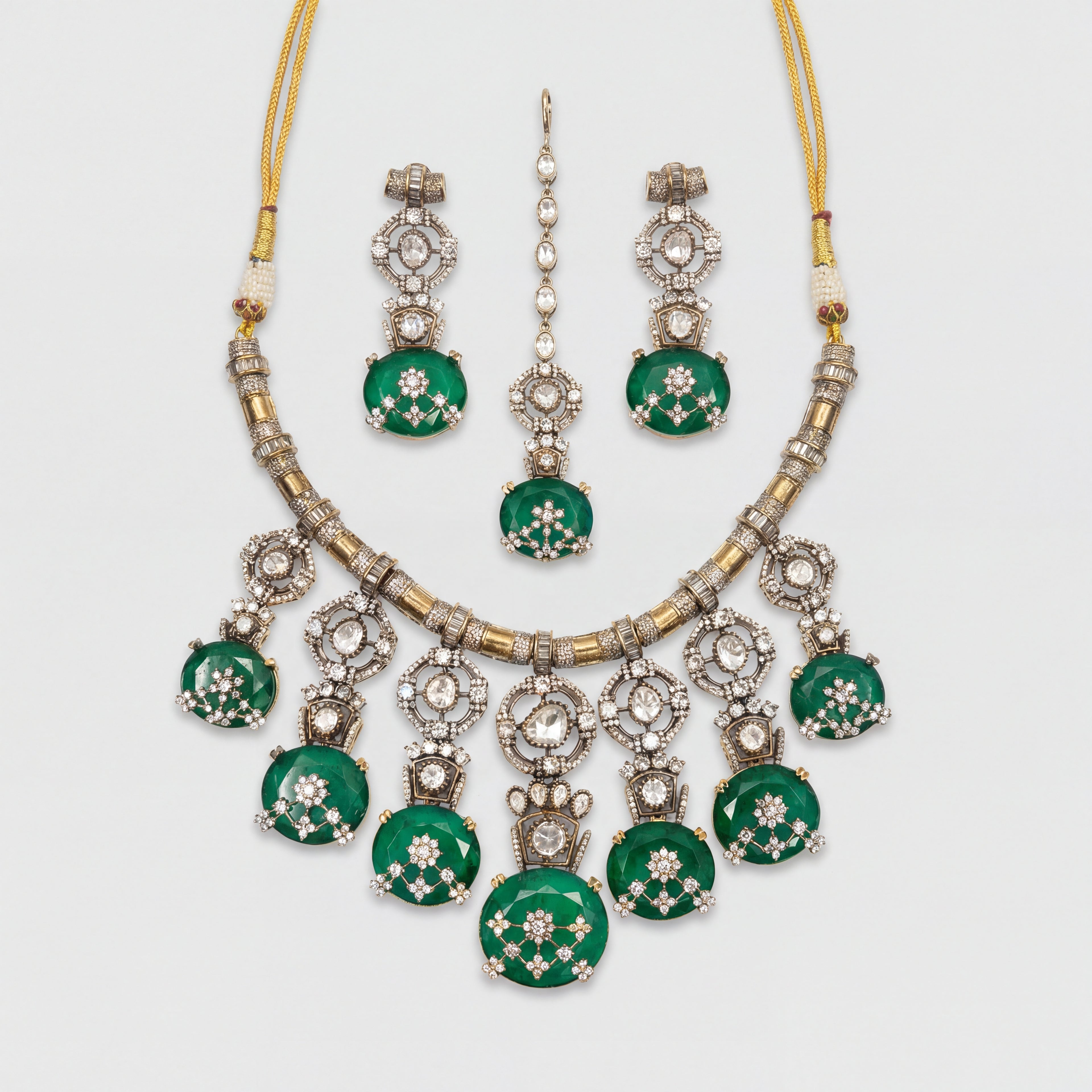 Zaira Emerald Necklace Set silver collar necklace with emerald pendants, earrings, and maang tikka on gray background