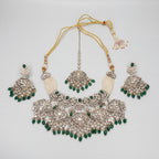 Inara Emerald Necklace Set silver bib necklace with green bead fringe, chandelier earrings, and maang tikka on gray background