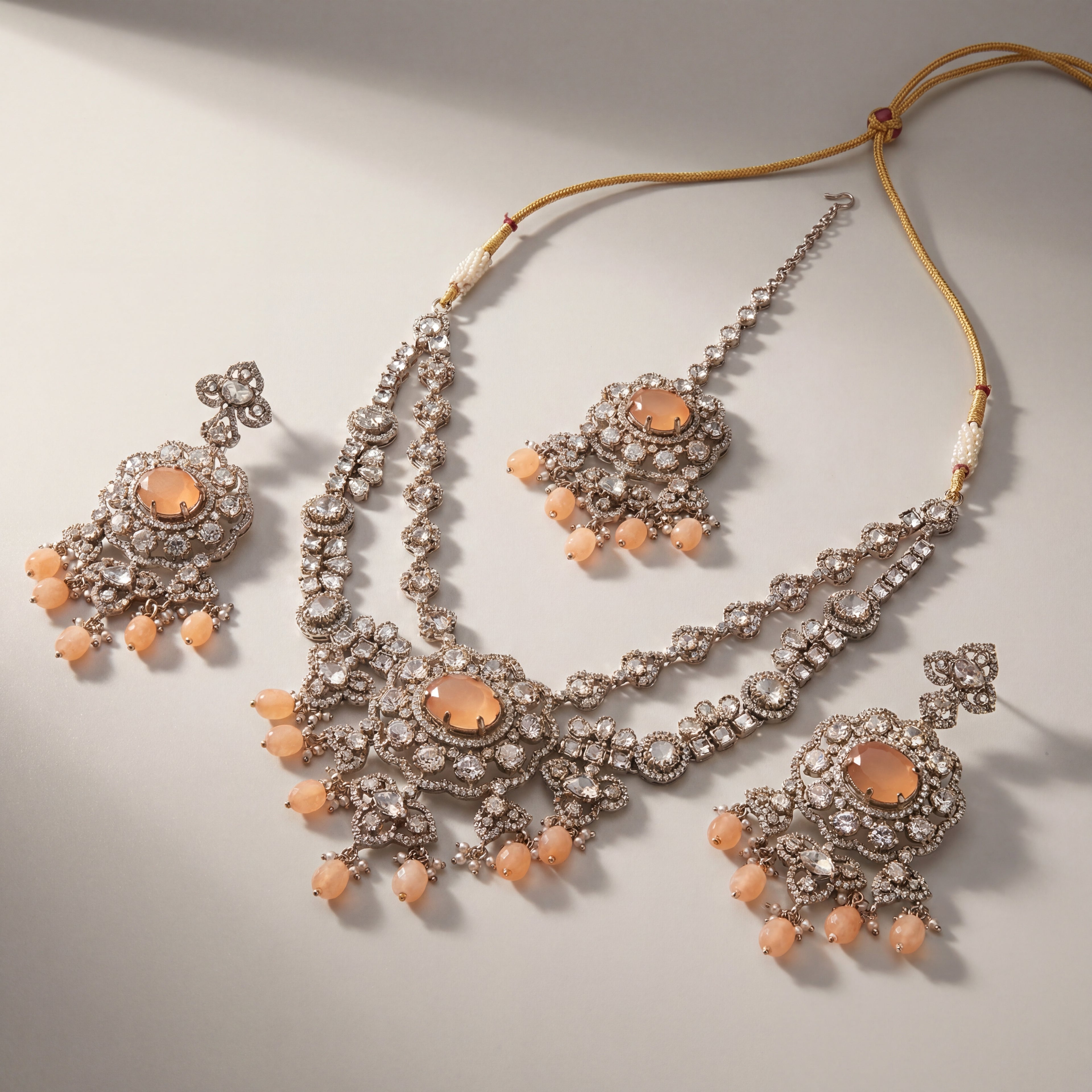 Aria Peach Necklace Set detail showing peach cabochon center, crystal floral border, and teardrop bead fringe