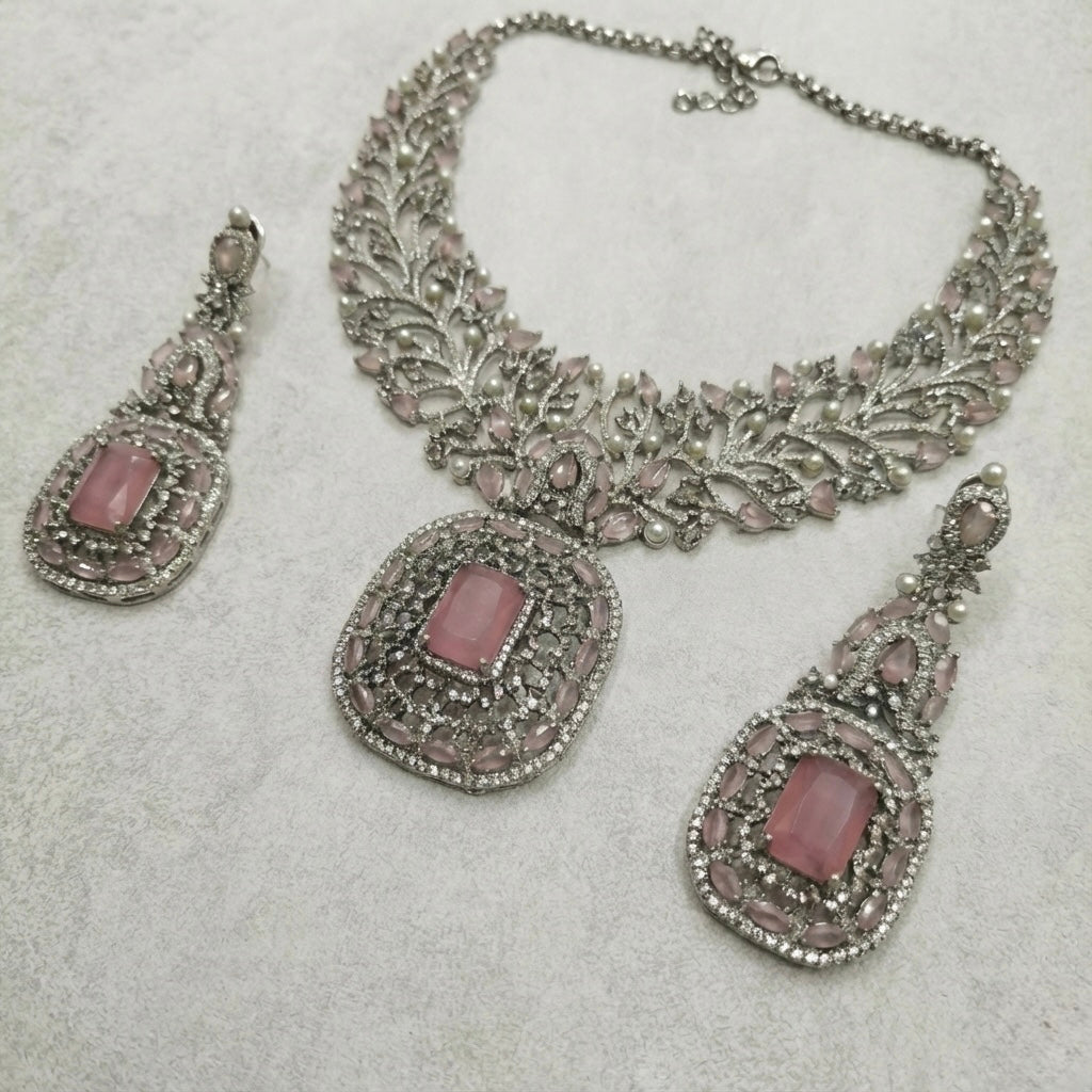 Detail flatlay of the silver-tone rose quartz necklace and matching earrings with blush pink stones