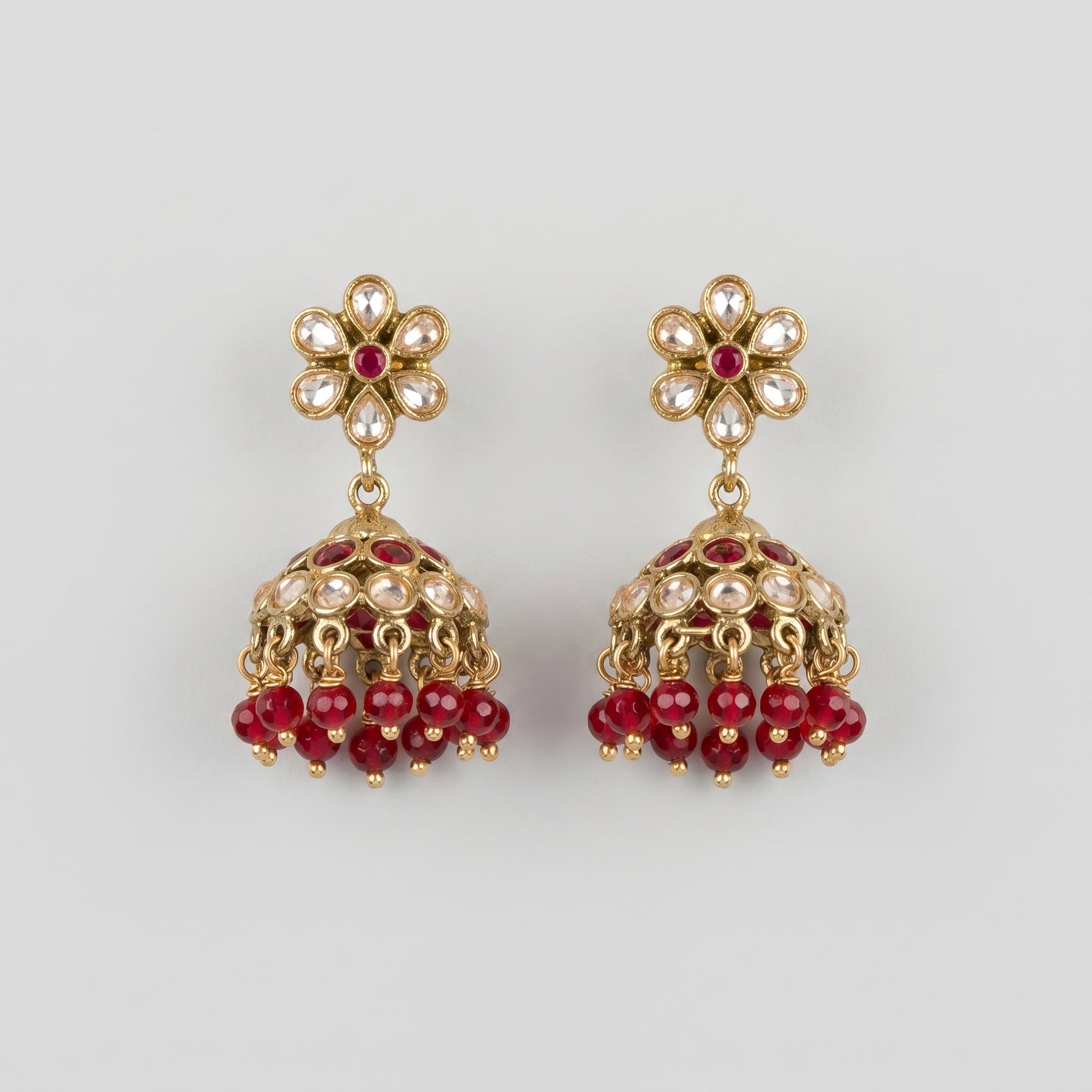 Amrita Ruby Earrings gold kundan jhumkas with ruby and clear stones on gray background
