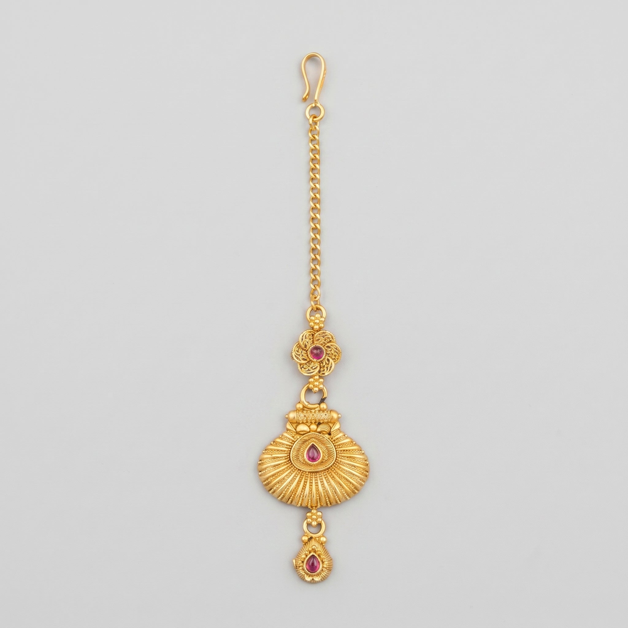 Priya Ruby Tikka matte gold maang tikka with ruby-pink stones on gray background