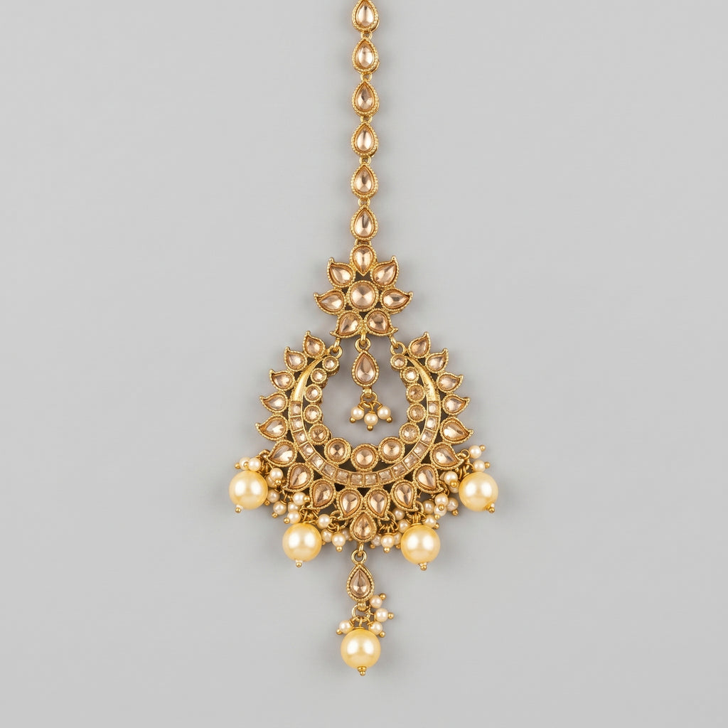 Jadau Pearl Tikka gold chandbali maang tikka with champagne stones and cream pearl drops on gray background