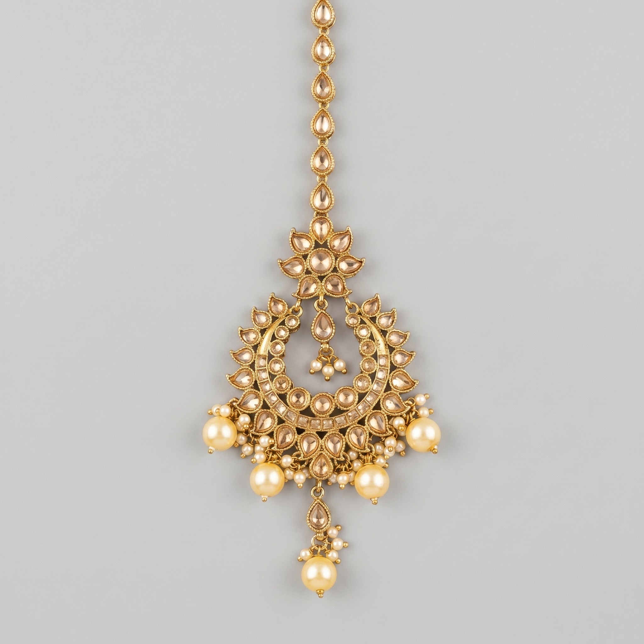 Jadau Pearl Tikka gold chandbali maang tikka with champagne stones and cream pearl drops on gray background