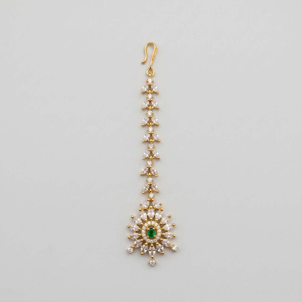 Emerald Star Tikka gold-tone maang tikka with green starburst pendant on gray background