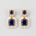 Neelam Enamel Earrings gold Art Deco drops with blue square stones and white enamel borders on gray background