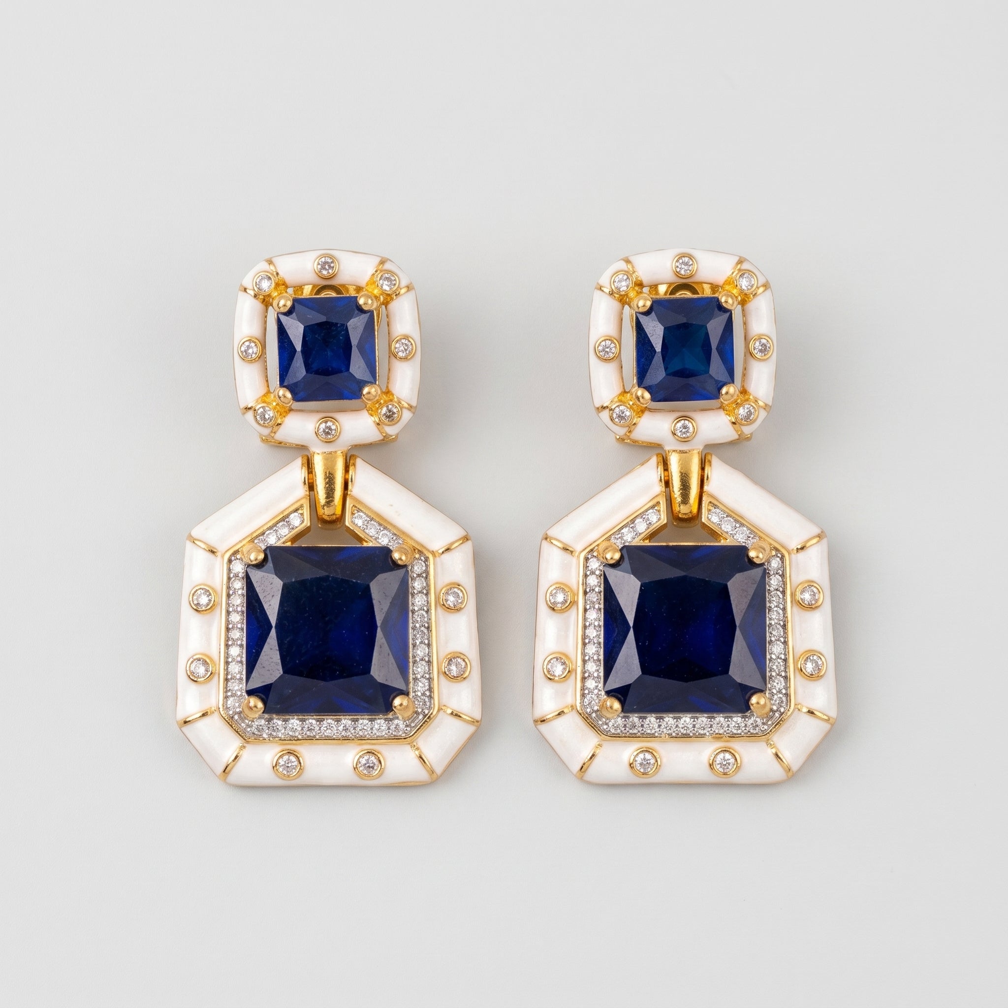 Neelam Enamel Earrings gold Art Deco drops with blue square stones and white enamel borders on gray background