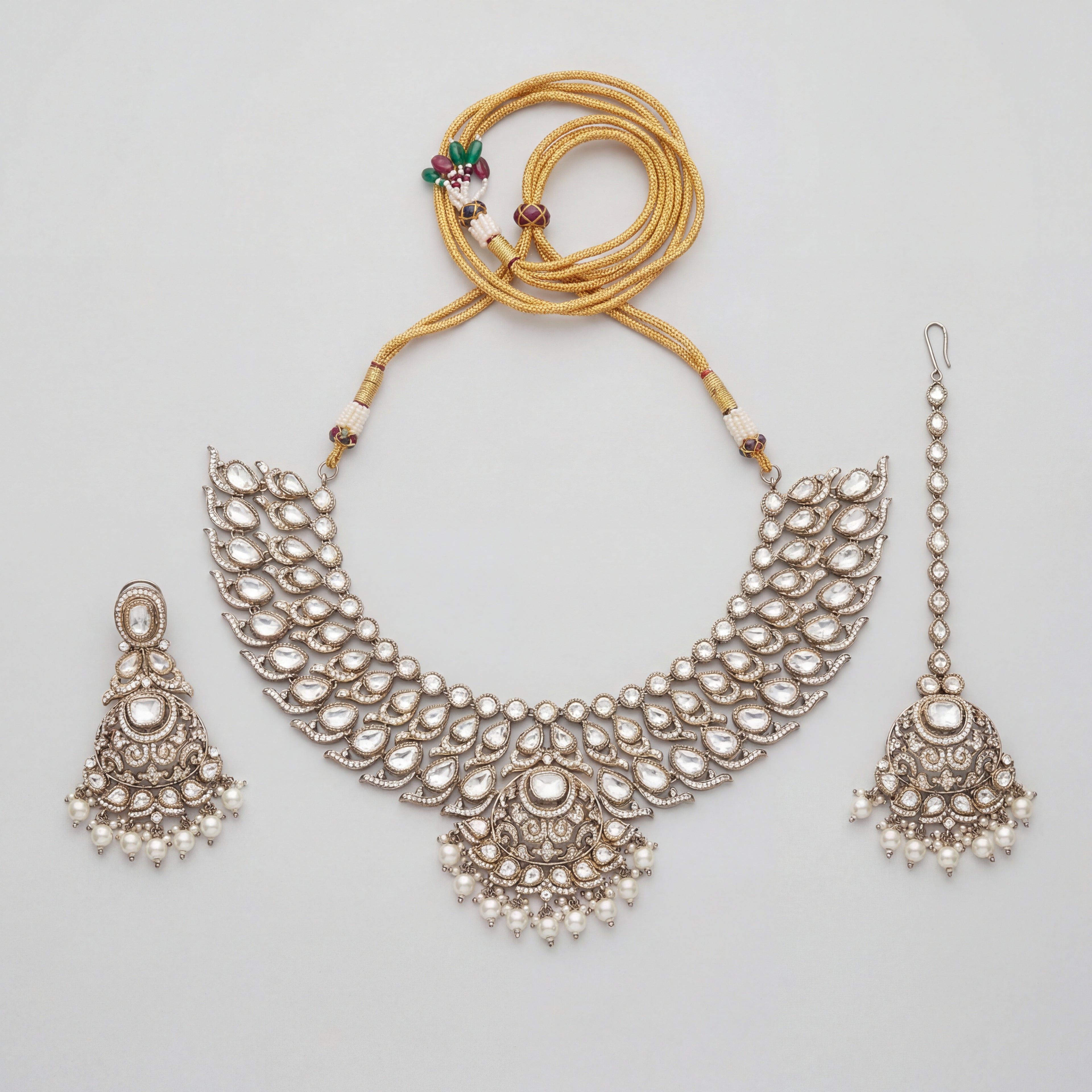 Jadau Pearl Necklace Set silver jadau bib with pearl fringe, matching earring, and maang tikka on gray background