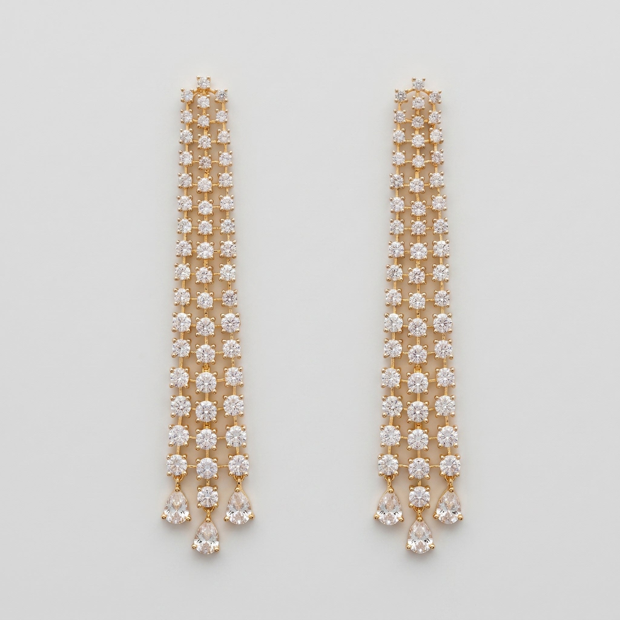 Hira Stream Earrings gold-tone crystal waterfall chandelier earrings with pear teardrop drops on gray background