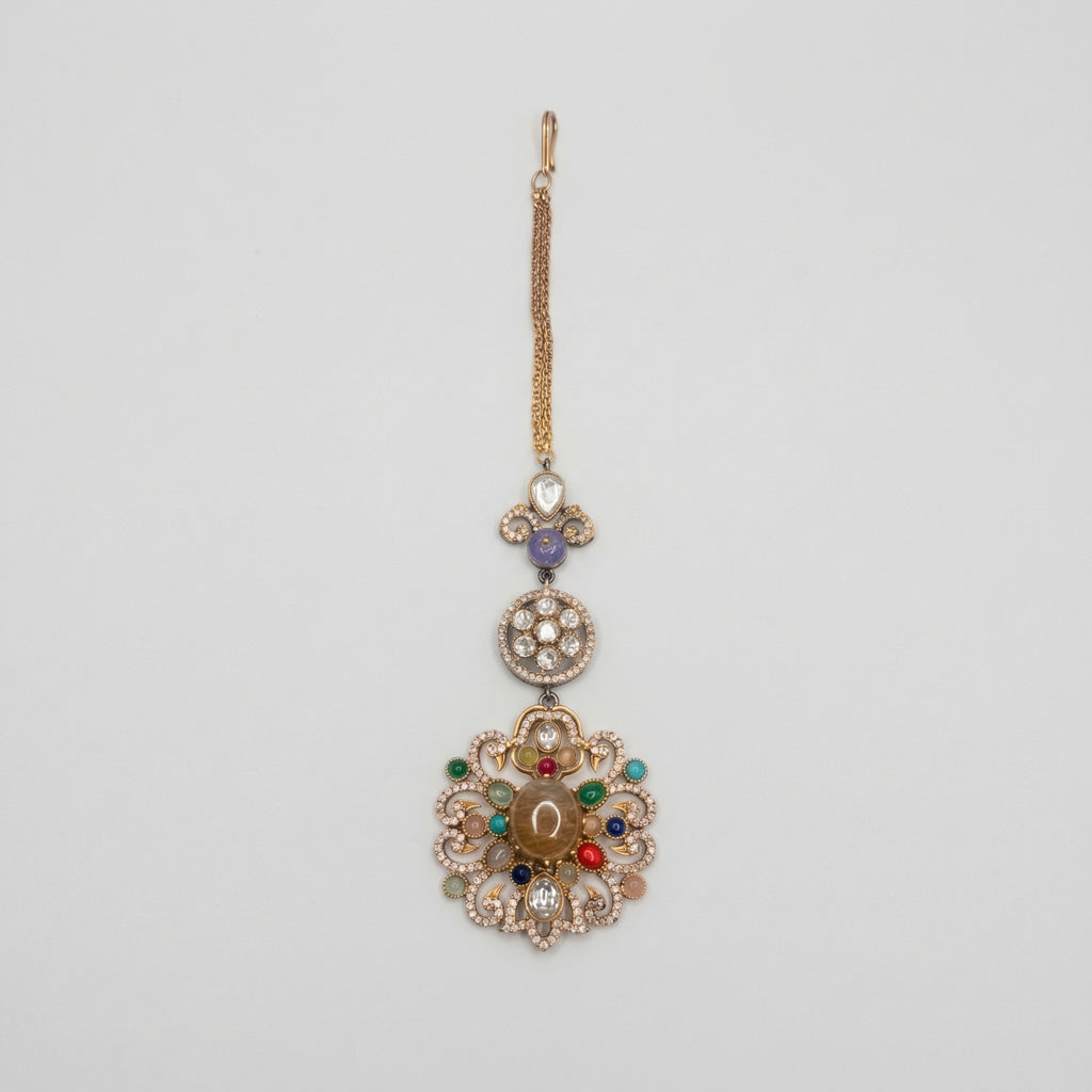 Navrang Tikka detail showing stacked medallions and oxidized gold scrollwork with colored stones