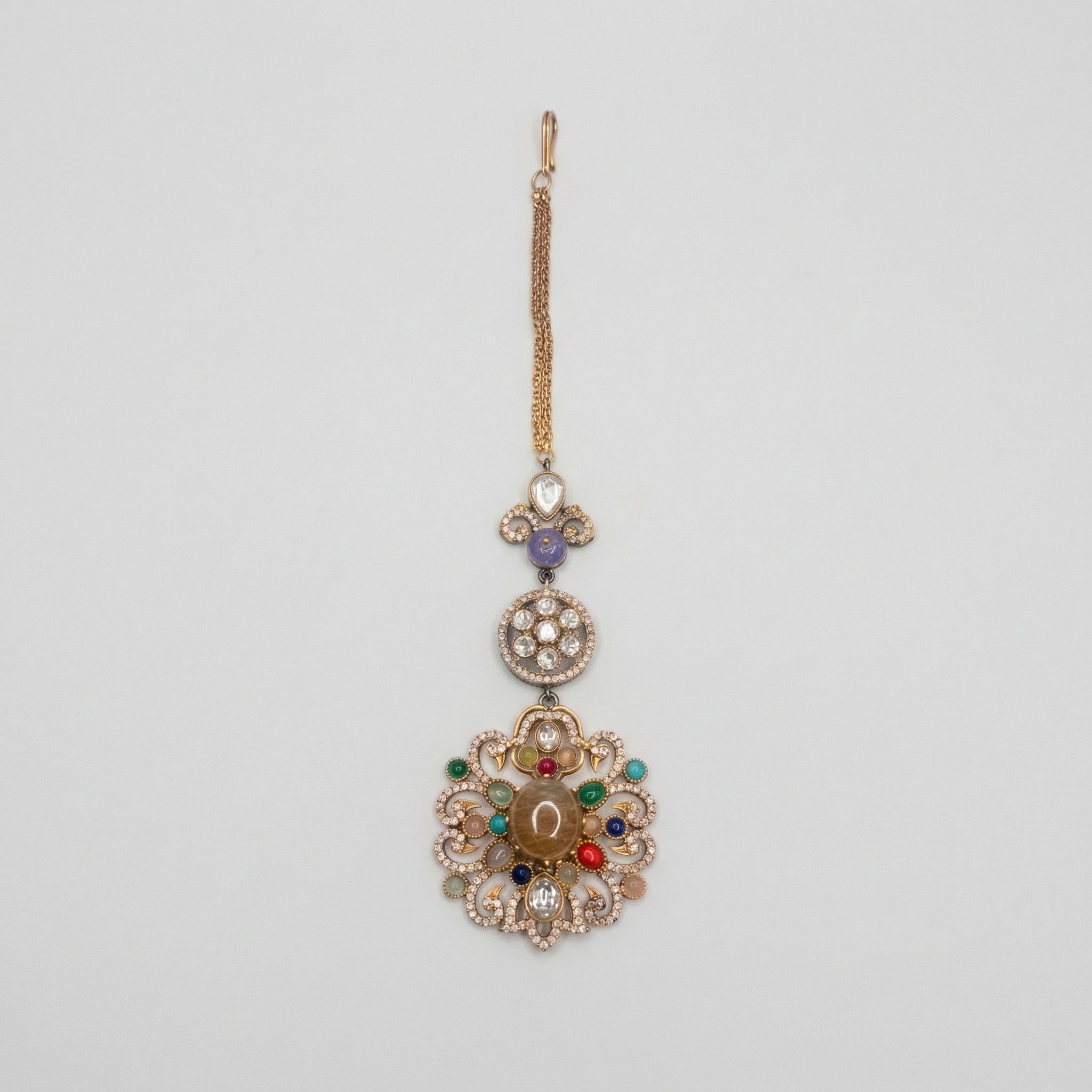 Navrang Tikka detail showing stacked medallions and oxidized gold scrollwork with colored stones