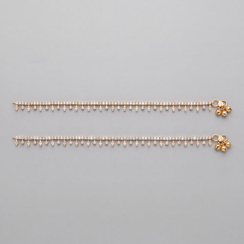 Flat lay of matching Kiran Starlight Anklets, clear pear and marquise stones with textured gold-tone bell clusters