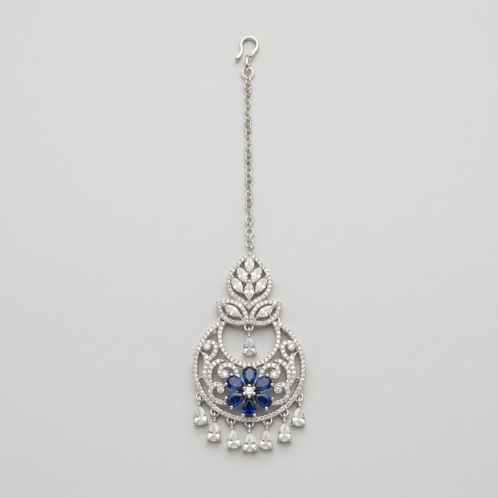 Adah Sapphire Tikka silver maang tikka with blue floral center and clear teardrop dangles on gray background