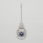 Adah Sapphire Tikka silver maang tikka with blue floral center and clear teardrop dangles on gray background