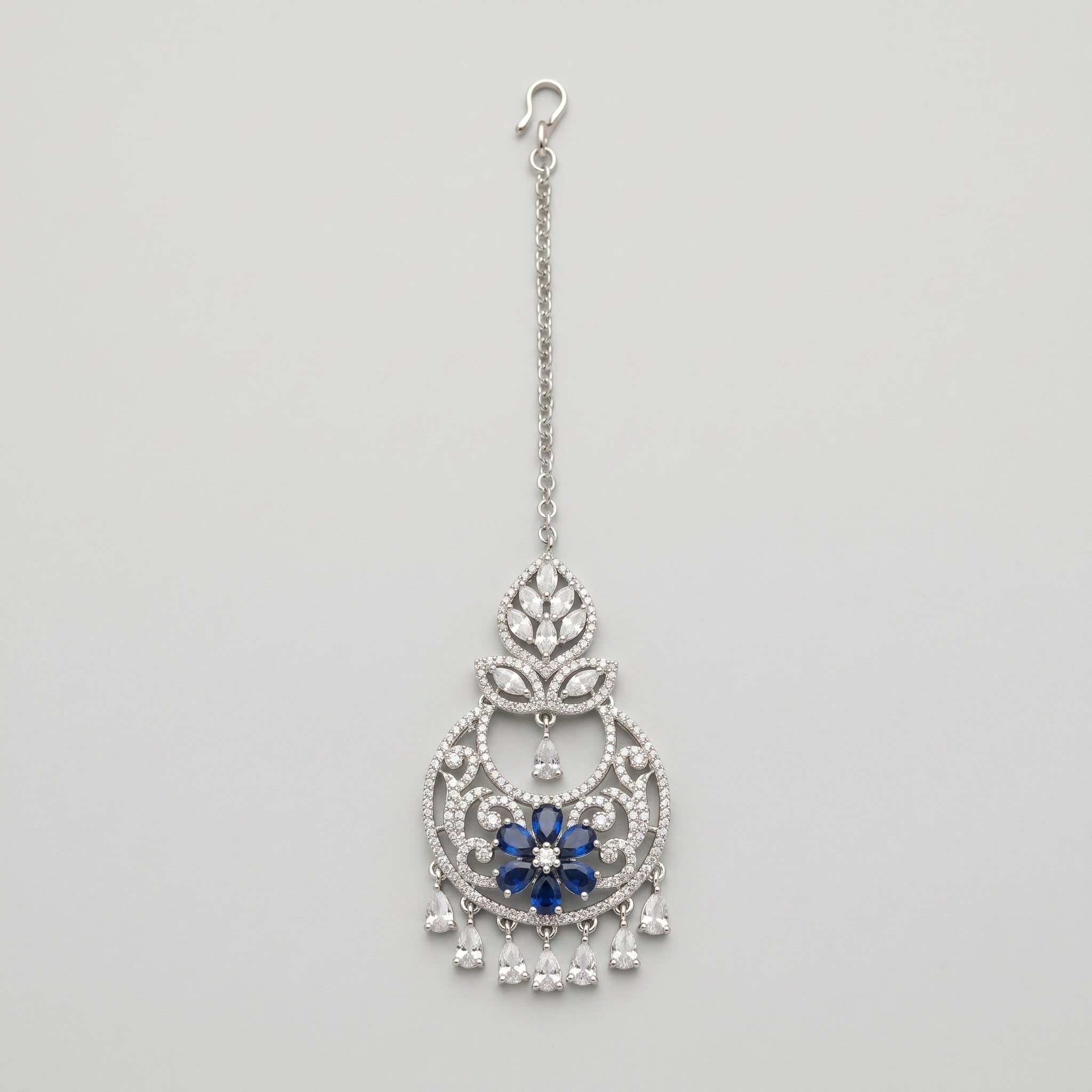 Adah Sapphire Tikka silver maang tikka with blue floral center and clear teardrop dangles on gray background