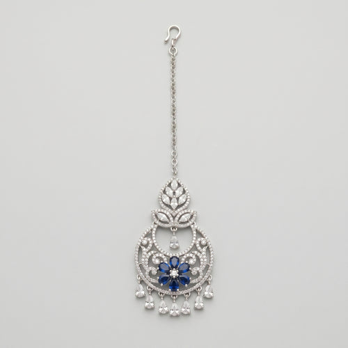 Adah Sapphire Tikka silver maang tikka with blue floral center and clear teardrop dangles on gray background