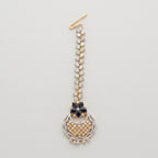 Rani Sapphire Tikka dual-tone maang tikka with blue floral accent and crescent crystal pendant on gray background