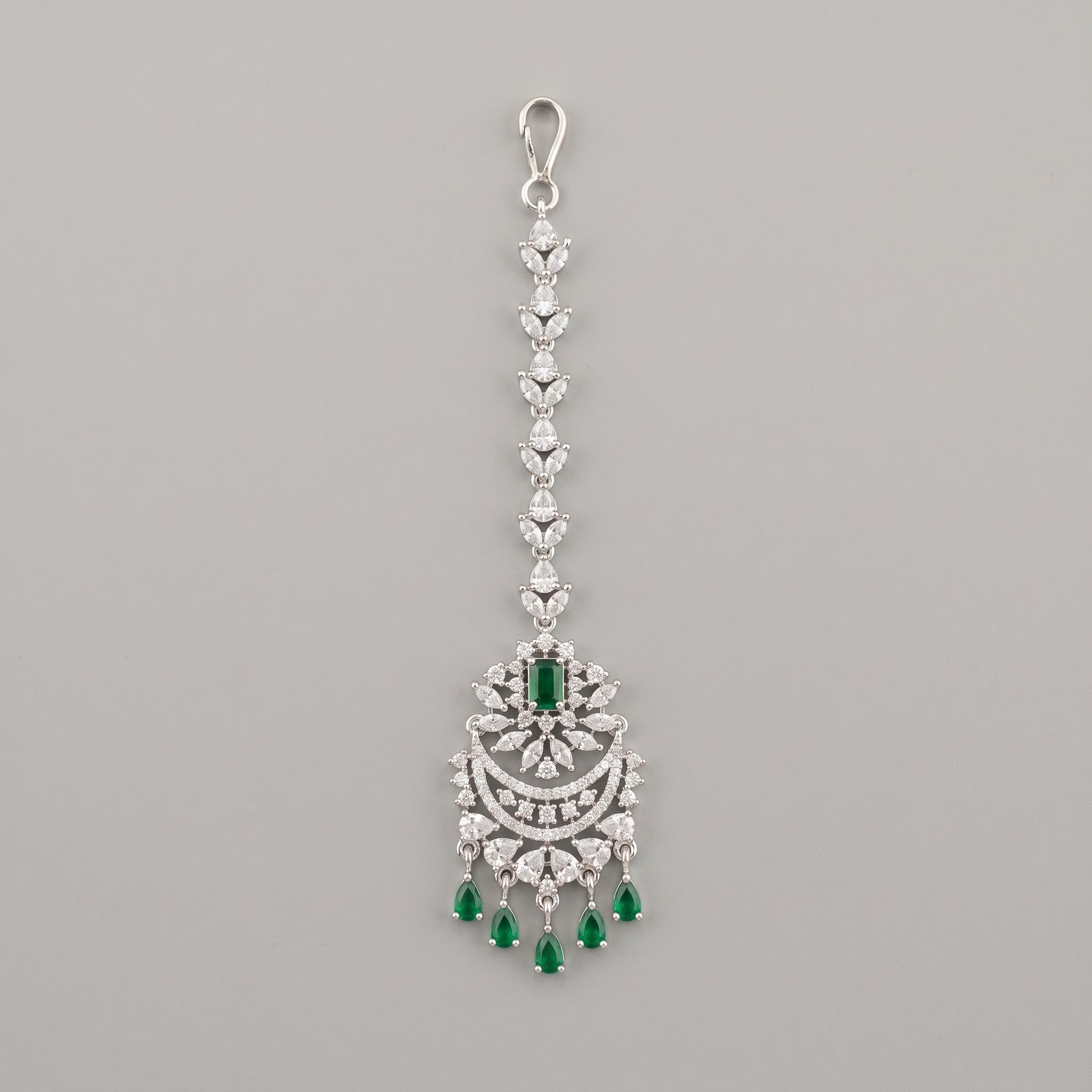 Sia Emerald Tikka silver maang tikka with green stones and chaandbali pendant on gray background
