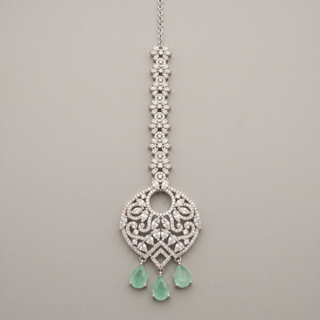 Panna Crystal Tikka silver-tone maang tikka with green teardrop drops on gray background