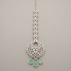 Panna Crystal Tikka silver-tone maang tikka with green teardrop drops on gray background