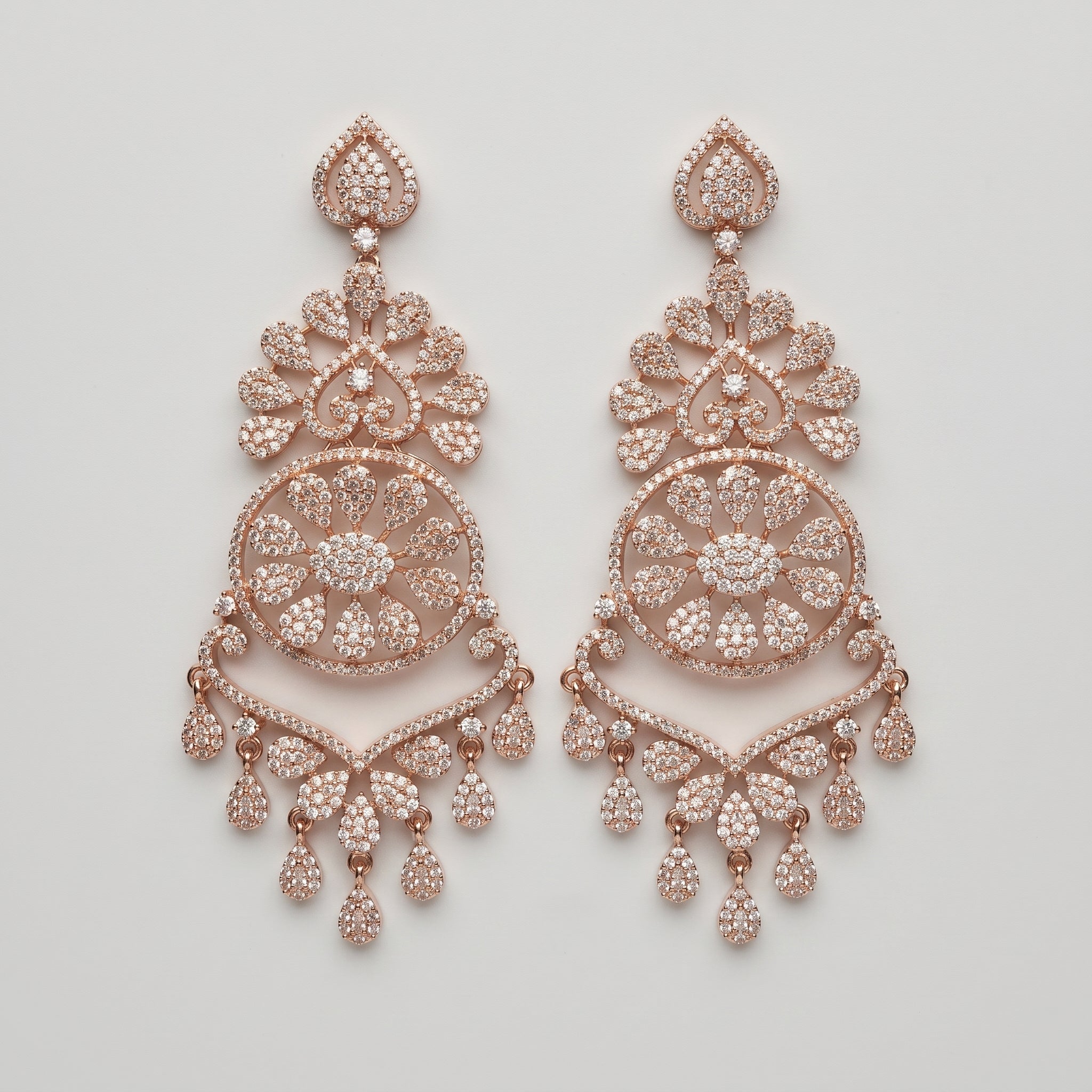 Roshni Earrings rose-gold chandelier drops with filigree medallion and crystal teardrop fringe on gray background