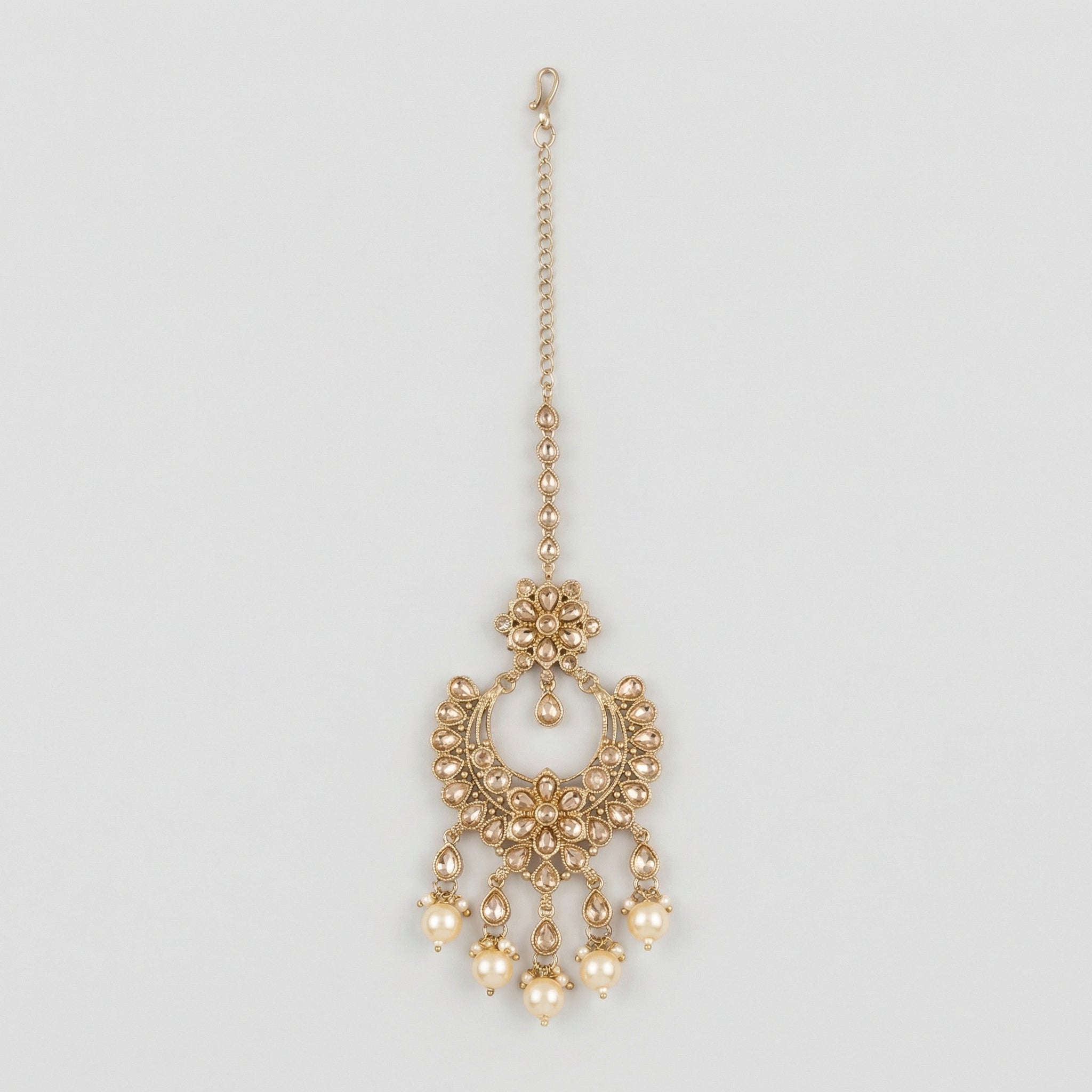 Kashi Pearl Tikka gold chandbali maang tikka with champagne stones and cream pearl drops on gray background