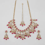 Rani Necklace Set gold kundan bib with pink stones, chandbali earrings, and maang tikka on gray background