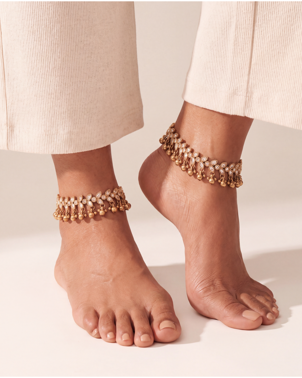 Matching Kiran Gilded Anklets worn as a pair, gold-tone chain with clear pear stones and bell drops