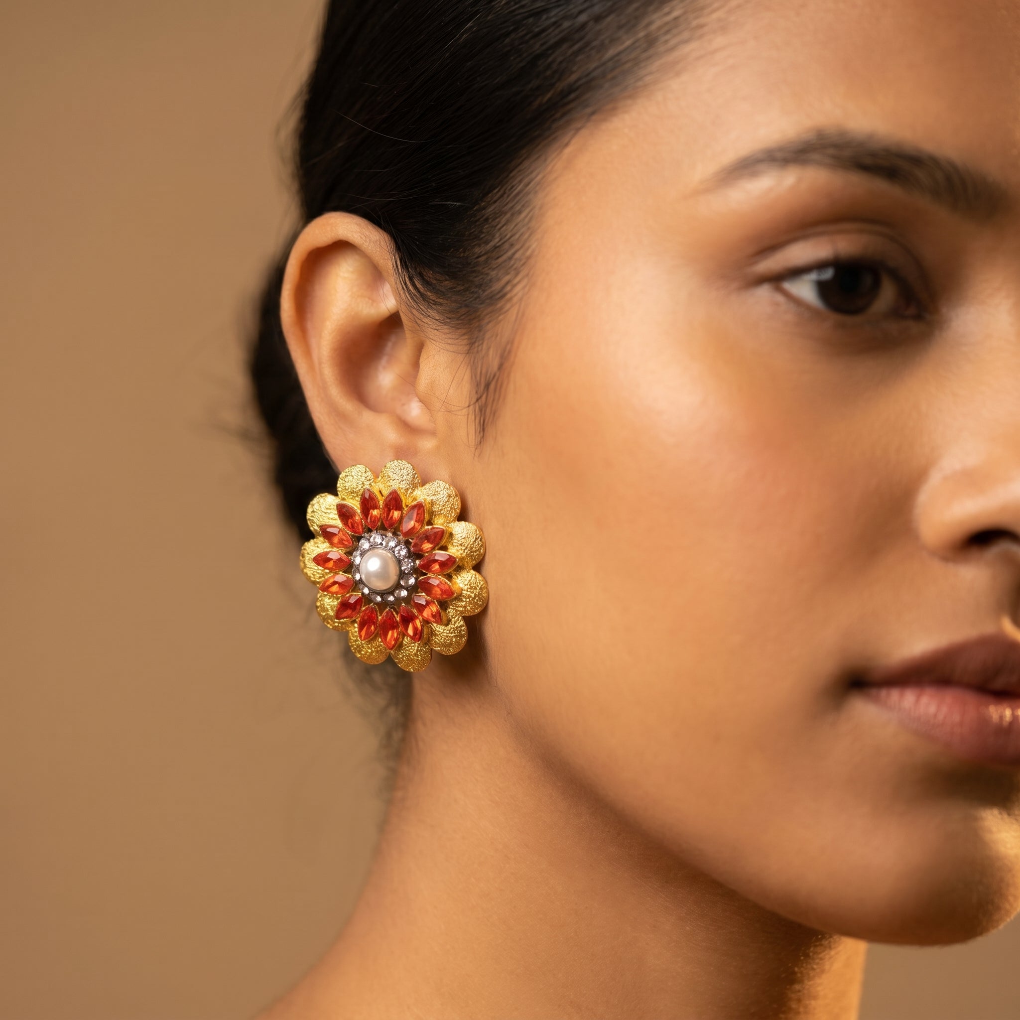 Manik Bloom Earrings detail showing crystal halo orange-red stones and hammered gold petals