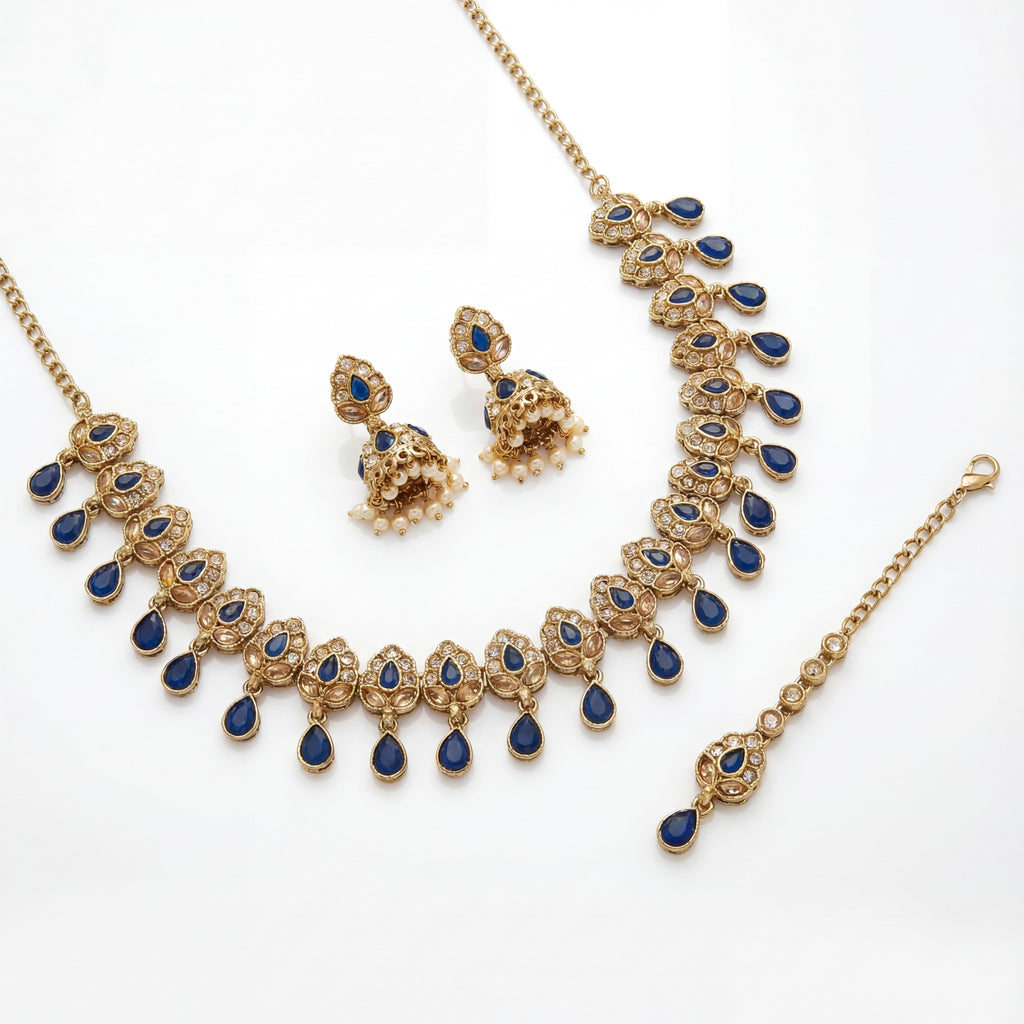 Detail flatlay of the gold-tone polki necklace and matching earrings with blue accents