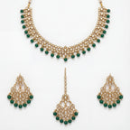 Anaya Emerald Kundan Necklace Set flat lay with gold-plated necklace, matching earrings, and tikka for Indian bridal