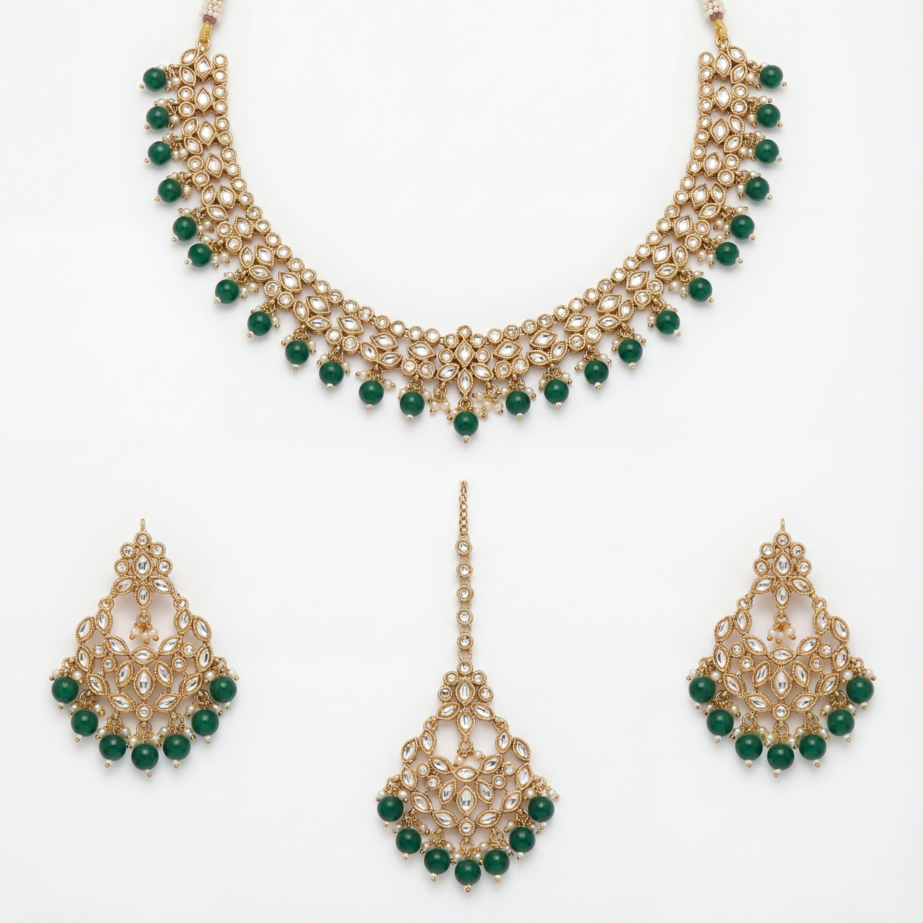 Anaya Emerald Kundan Necklace Set flat lay with gold-plated necklace, matching earrings, and tikka for Indian bridal